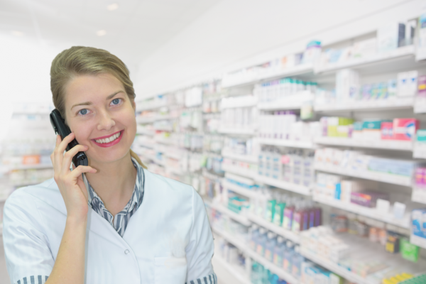 Une spécialiste parle au téléphone devant un rayon de médicaments